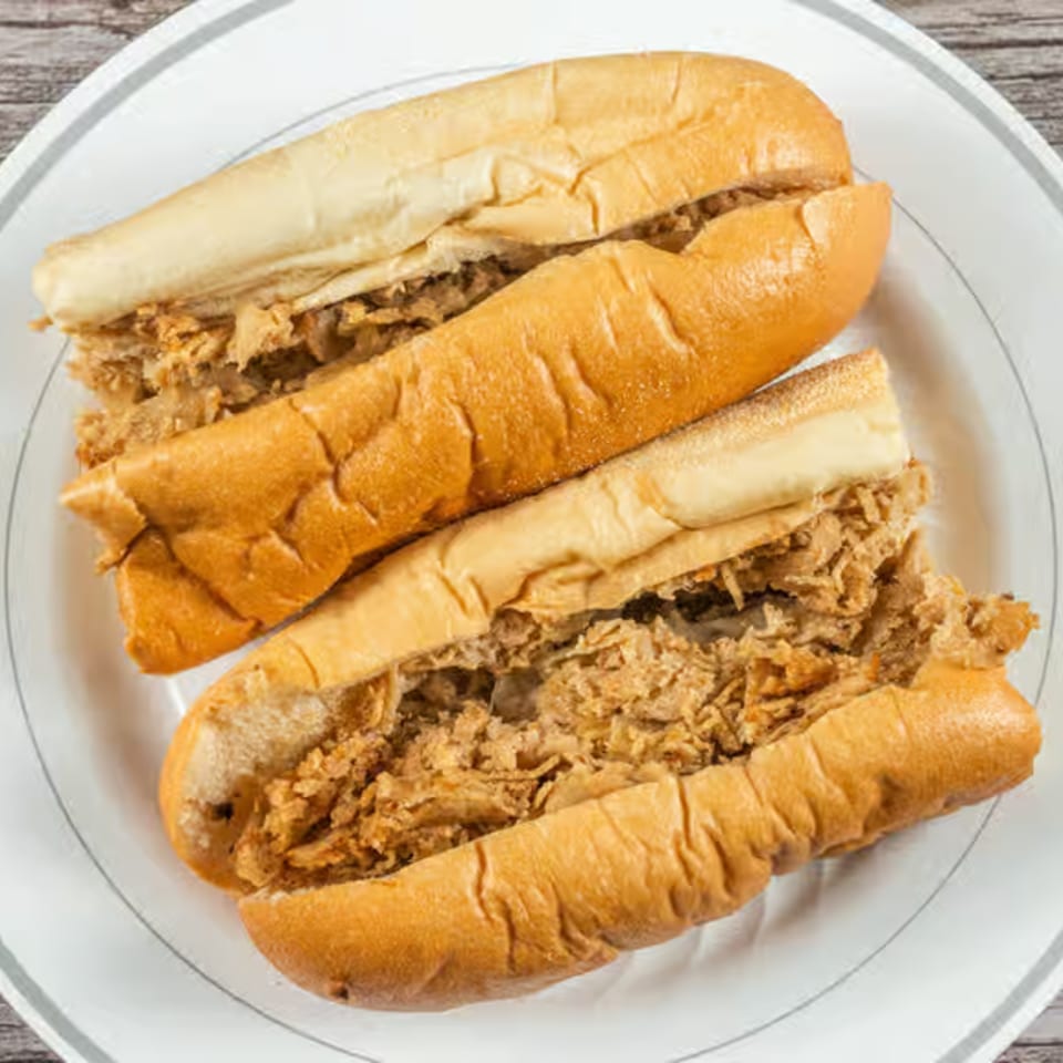 Two long sandwiches with shredded meat filling, served on a white plate.
